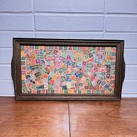 Front view of vintage wooden tray filled with colorful international postage stamps.