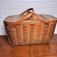 Front view of the vintage woven picnic basket showing the detailed woven wood construction and dual handles.