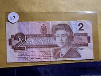 Front side of the 1986 Canadian $2 dollar bill showing Queen Elizabeth II portrait and numeric denomination 2 with banknote serial numbers and signatures.