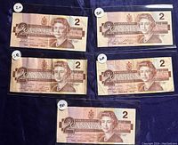 Front view of five 1986 Canadian $2 bills showing Queen Elizabeth II portrait and denomination markings.