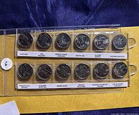 Two plastic holders containing 12 Canadian 25 cent coins from 2010 Vancouver Winter Olympics series with each coin depicting a different Winter Olympic sport.