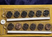 Plastic collector's holder containing 12 Canadian 25 cent coins from the 2010 Vancouver Winter Olympics series arranged in two rows.