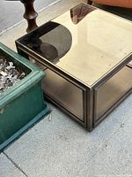 Top-down angled photo showing smoked glass top and dark wood frame of the square side table.