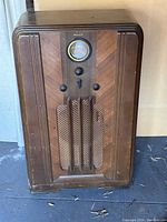 Front view of Philco radio showing dial, control knobs, and wood finish with speaker grill.
