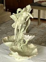 Full view of the porcelain vase with a woman and child figurative sculpture set on a floral leaf base forming the vessel.