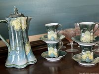 Full set displayed with carafe, cups stacked on saucers