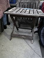 Side view of one wooden foldable table showing weathered paint and slatted top