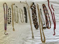 Full view of 10 costume necklaces arranged on fabric background showing diverse colors and materials including beads and linked elements