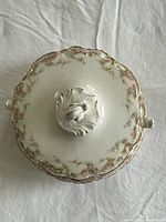 Top view of soup tureen lid showing pink flower border and ornate knob