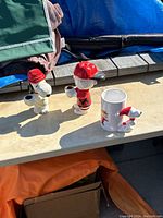 Two Snoopy-themed ceramic candlestick holders and one holiday Snoopy mug on a concrete surface.