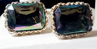 Close-up front view of the pair of vintage emerald cut stone cufflinks showing the rectangular faceted iridescent stones with beaded silver-tone frames.