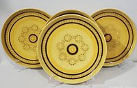 Three 1970s Franciscan dinner plates with yellow honeycomb pattern displayed upright on stands, showing overall design and condition.