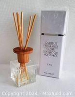 Diffuser bottle with wooden cap and reed sticks next to original box