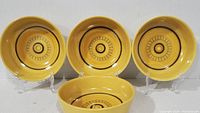 Four yellow Franciscan coupe cereal bowls arranged with three on plate stands and one upright in front, showcasing interior honeycomb pattern and overall condition.