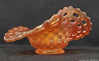 Side profile of marigold carnival glass basket showing basket weave texture and open edge design.
