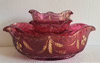 Front view of stacked ruby flash glass bowls showing ruffled edges and gold leaf decoration