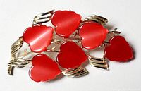 Front view of red heart CORO brooch showing glossy heart shapes and gold-tone leaf accents.