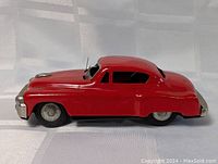 Right side view of the red tin friction car showing the body shape and wheels.