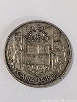 Close-up of one side of the 1954 Canadian silver half dollar coin showing detailed coat of arms and denomination clearly visible.