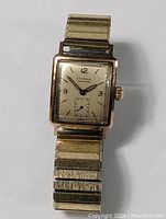 Front view of antique gold plated Eterna Mend watch showing rectangular case, dial, hands, and band.