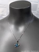 Front view of necklace showcased on a black mannequin bust. The starfish pendant with blue inlay is centered and hanging from a fine silver chain approximately 19 inches in length.