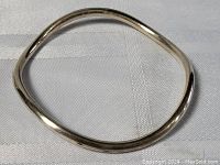 Top down view of the silver bangle showing its abstract irregular shape and polished surface.