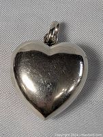 Front view of polished sterling silver heart pendant showing smooth surface.