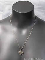 Front view of the pendant on a black display bust showing the pendant hanging from the chain.