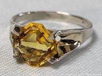Front angled view of sterling silver ring with yellow faceted stone showing prong setting and polished band.
