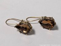 Pair of sterling silver hook earrings with pear-shaped smokey brown faceted stones set in prongs.
