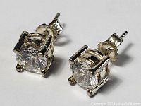 Pair of sterling silver stud earrings featuring clear, faceted gemstones in four-prong settings with butterfly backs.