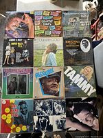 Photo showing 12 vintage vinyl records arranged in rows. Album covers visible include Johnny Cash, Jeannie C. Riley, Nat King Cole, Tammy soundtrack, and more.