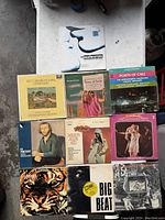 Photo of nine vintage vinyl records arranged on a table, showing album cover art and titles.