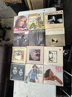 Photo showing the full lot of 11 vinyl records laid out on a table and the floor.