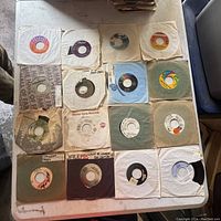 Top view showing 20 vintage 7-inch vinyl records in paper sleeves on a table.