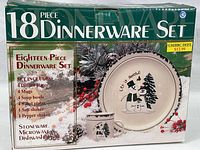Photo of original box front showing 18-piece dinnerware set with Christmas snowman themed plates, mugs, and shakers. Box displays set contents and mentions stoneware, microwave and dishwasher safe.