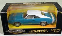 Front and side view of the 1969 Dodge Charger R/T die cast model in original packaging showing blue body, white roof, and detailed interior.