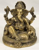 Full view of the brass Ganesh figure seated on a decorated base showing the full body and detailed ornaments.