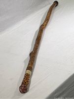 Full length of walking stick showing carved wood shaft and rubber tip.