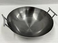Image showing top view of a large stainless steel wok with round bottom and two sturdy steel handles on opposite sides.