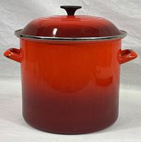 Full front view of the stock pot showing cherry cerise red gradient finish with handles and lid in place.