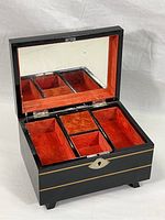 Open box showing red velvet interior with four compartments and interior mirror on lid.