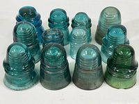 Lot of 12 blue and green vintage glass electrical insulators from front, showing size and color variations