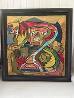 Full view of framed abstract painting with multiple colors and abstract faces