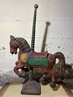Front and side view of wooden carved carousel horse mounted on twisted pole with square base, painted in vibrant colors.