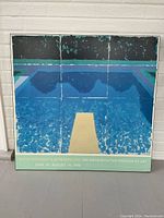 Full front view of the laminated board print showing David Hockney's pool artwork with text at bottom edge noting the exhibition dates and museum.