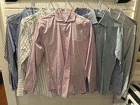 Front view of 7 assorted men's dress shirts, size medium, hanging on hangers showing different colors and patterns including pink, striped, blue, and grey.