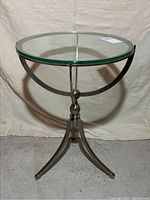 Front angle view of the round glass top and three-legged chrome base end table.