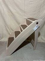 Side view of pet steps showing four steps with brown non-slip pads and smooth curved plastic sides.