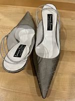 Top view of the pair of pointed toe silver raw silk sling back kitten heel shoes showing the interior and brand label.